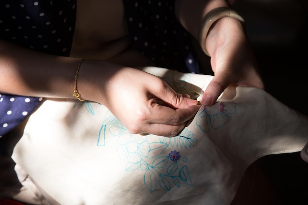 mâini lucrând o broderie detaliată